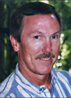 Short-haired male with blue striped shirt. Mustache and smiling.