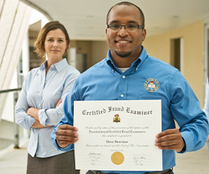 image of man proudly holding his CFE Certificate with woman behind looking on