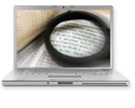 Laptop screen showing a magnifying glass over a page of a book.