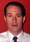 Male adult with short dark hair wearing striped dress shirt and black tie